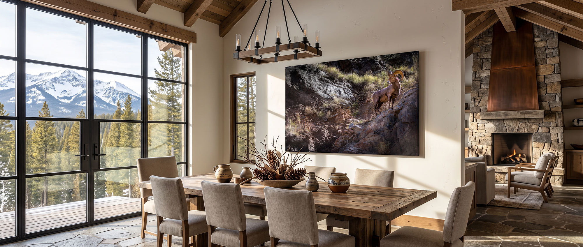 A large framed landscape art print depicting a horse running through a rocky mountain stream, displayed on a beige wall in a rustic dining room with a wooden dining table, chairs, and a stone fireplace.