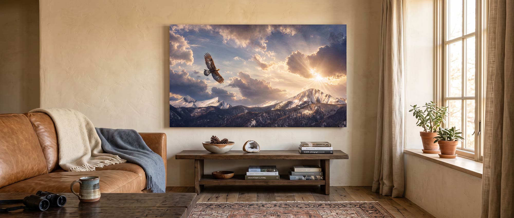 A large framed wall art print depicting a dramatic mountain landscape with a flying eagle, displayed in a styled living room above a wooden console table.