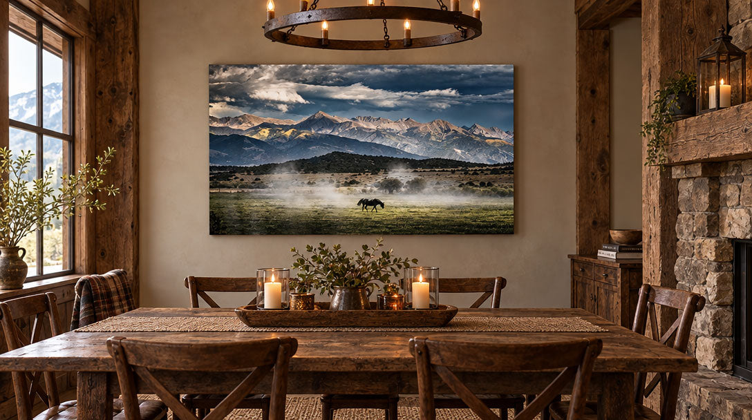A large rectangular canvas print of a mountain landscape with a horse, displayed on a rustic wooden dining room wall above a dining table.