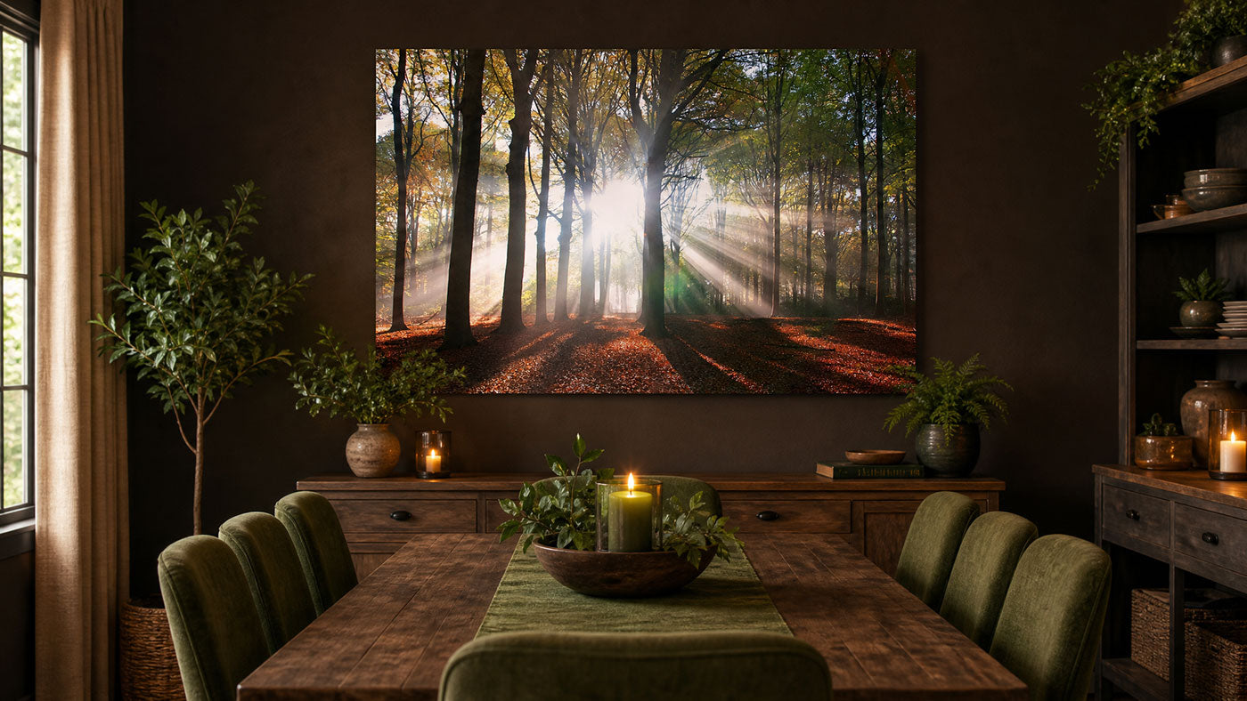 A large framed forest wall art print hangs above a wooden dining table in a dark, elegant dining room. The artwork depicts sunbeams filtering through a forest with golden light on the floor.